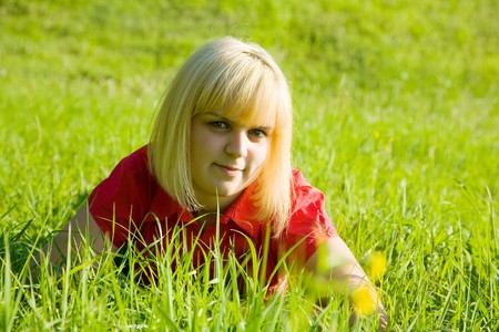 Smiling girl in red lying on meadow grassの写真素材
