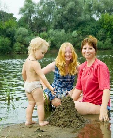 mother with children on river beach in summerの写真素材