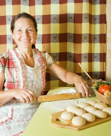 Woman cooking meat dumplings with rolling pinの写真素材
