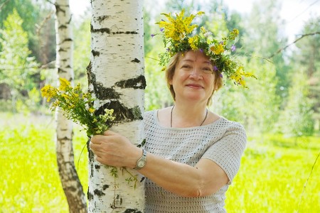 Portrait of mature woman near birch in flowers wreathの写真素材
