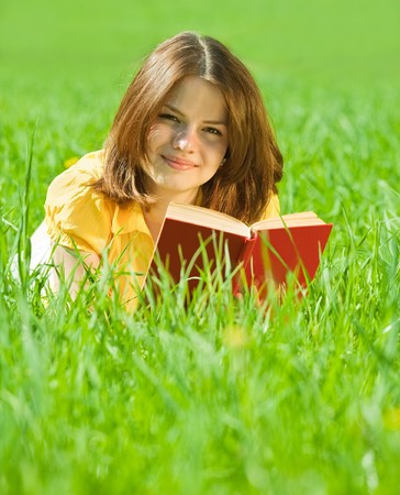 young  girl reading book in grass outdoorsの写真素材