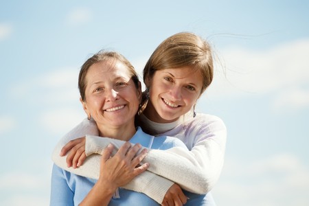 Portrait of mother with teen daughter against skyの写真素材