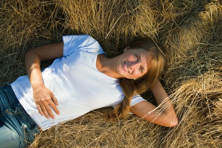 Pretty girl resting on fresh straw baleの写真素材