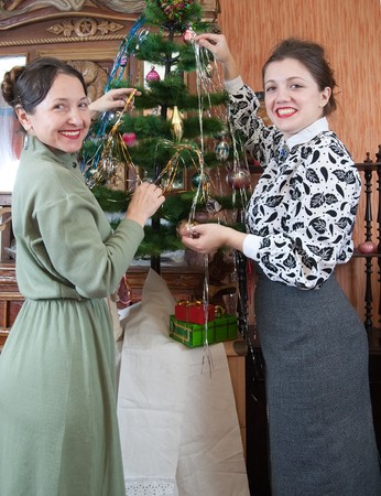 daughter with mother decorating Christmas tree at homeの写真素材