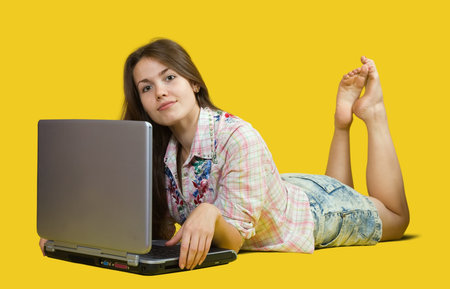  pretty young girl  with laptop. Isolated over yellow