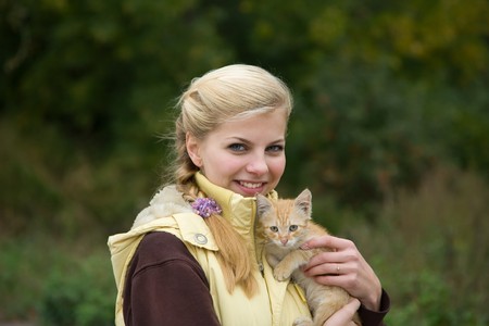 Portrait of smiling girl with kitten at against natureの写真素材