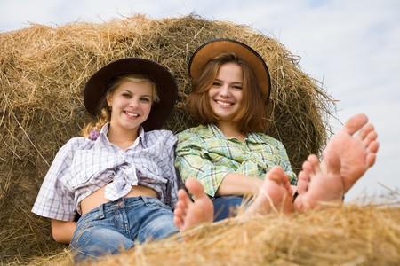 country girls restings on fresh hay baleの写真素材