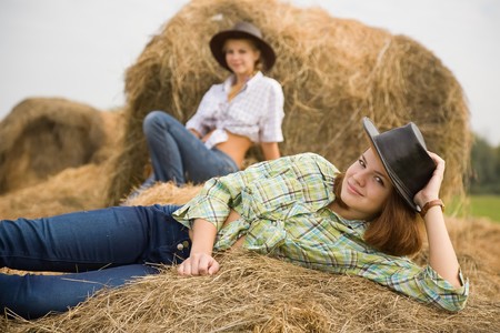 country girls laying on  hay bails in fieldの写真素材
