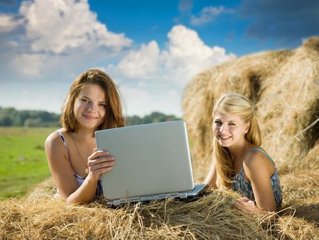 country girls with laptop on  hay at fieldの写真素材