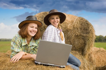 Two country girls with notebook on hay in farmの写真素材