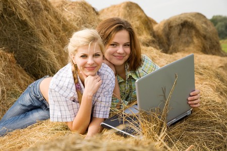 country girls with laptop on  hay at fieldの写真素材