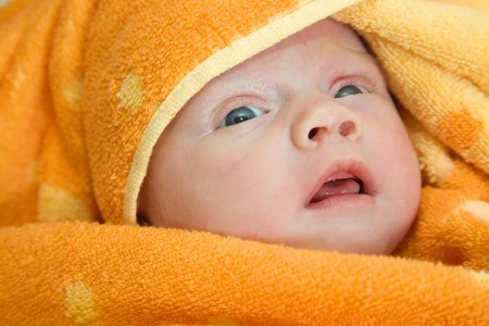 Newborn baby relaxing in orange warm blanketの写真素材