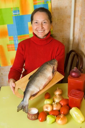 Woman with red fish in her kitchenの写真素材