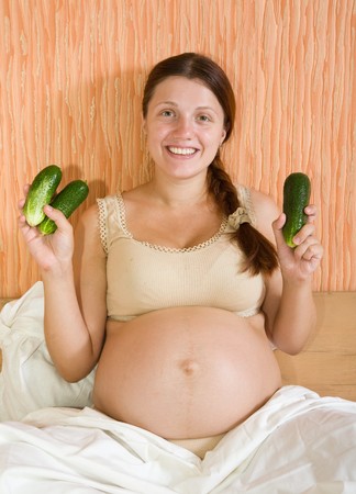 Beautiful and healthy pregnant woman with cucumbersの写真素材