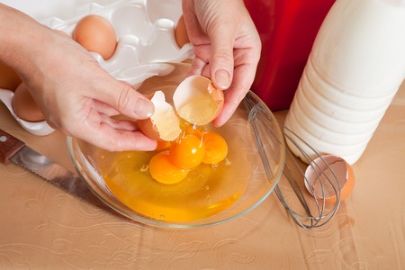 Cook hands adds eggs into dish.
One of the stages of cooking  omelet.  See seriesの写真素材