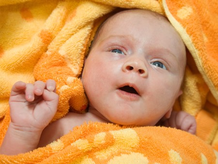 Newborn baby relaxing in orange warm blanketの写真素材
