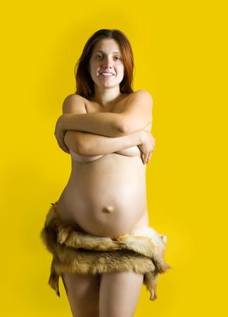 Portrait of 9 months pregnant woman in  fox fur  over yellowの写真素材
