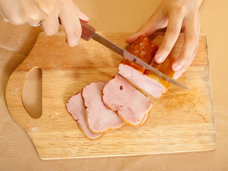 Closeup of cook hands cutting bacon on cutting board.One of the stages of preparation of bacon and...