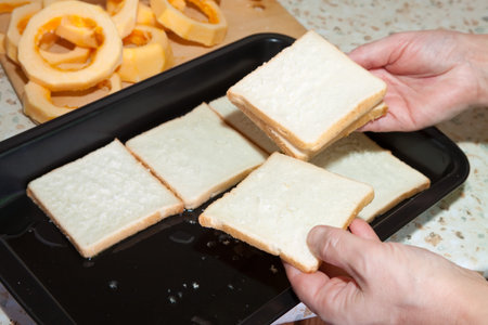 Cook puts toast bread into roasting pan.See in series stages of cooking of stuffed vegetable marrow...