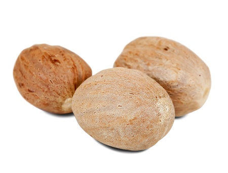 three full  nutmegs. Isolated on white backgroundの写真素材