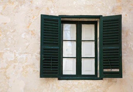  window with green shutters on old wall at mediterranean townの写真素材