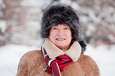 Outdoor winter portrait of mature woman in wintry clothes