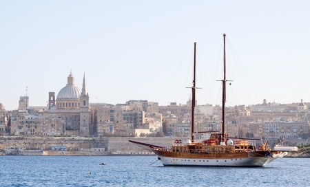 Vintage ship docked in creek against old town (Valletta, Malta)の写真素材