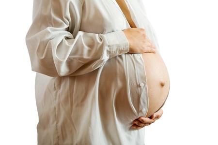 Belly of 9 months pregnant woman in white shirt over whiteの写真素材