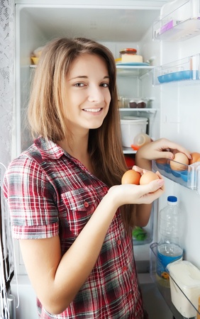 Teenager girl putting eggs into refrigerator  at homeの写真素材