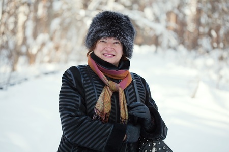 Happy mature woman is walking at winter parkの写真素材
