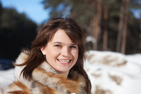 Portrait of smiling girl in fur coat at wintry parkの写真素材