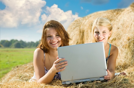 Young sweet girls relaxing with laptop outdoorの写真素材