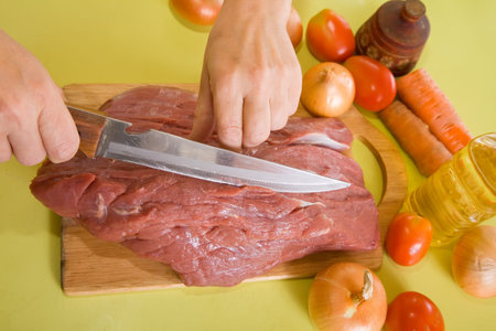 Closeup of cook hands cutting beef on cutting board.One of the stages of preparation of the stuffed...