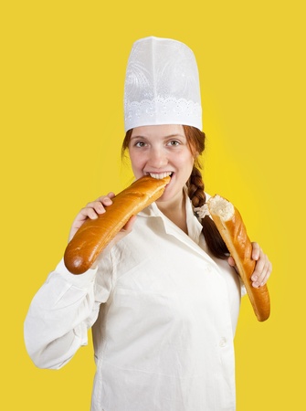 Woman is eating French long baton over yellowの写真素材