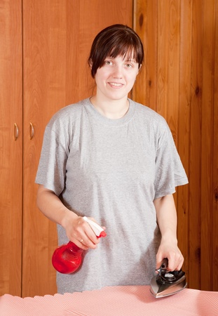 Happy young woman ironing a fabric at homeの写真素材