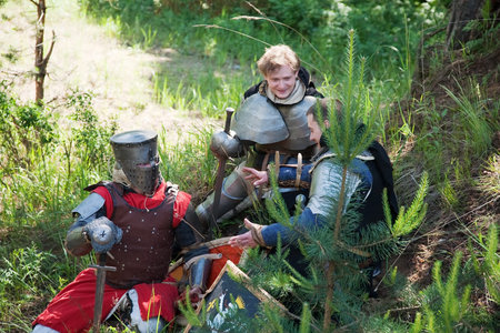 Knights in armour having bivouac at forest