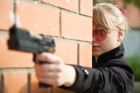 woman with gun against  the brick wallの写真素材