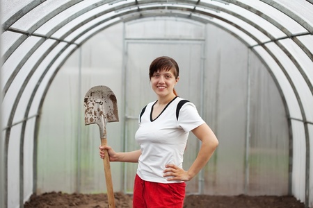 Happy female gardener with spade in hothouseの写真素材