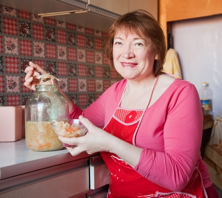 Woman with can of pickled cabbage at her kitchenの写真素材