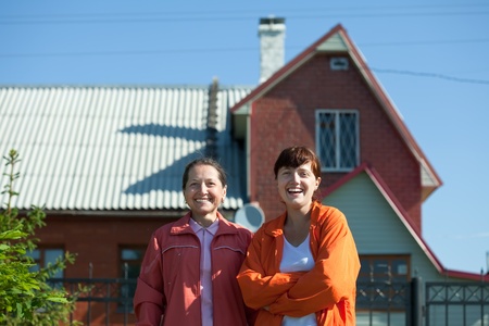 Two happy women against her homeの写真素材
