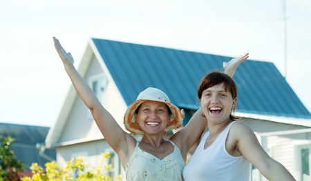 Two happy women  in front of new homeの写真素材