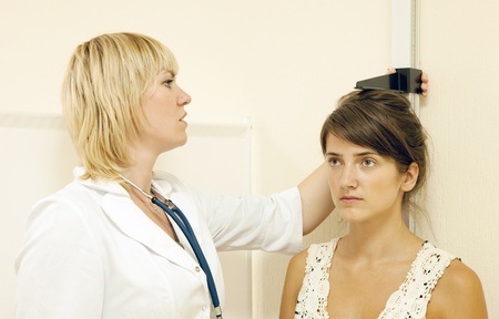 Woman measuring height of teenager patient in clinicの写真素材