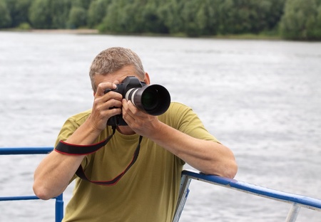 Male photographer  with photocamera  against riverの写真素材