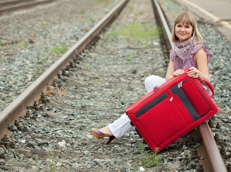 woman with luggage sitting on railの写真素材