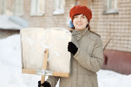 young woman with shovel in snowy streetの写真素材