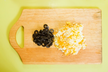 grated eggs and  sliced olives on cutting board See in series stages of cooking of stuffed tomato の写真素材