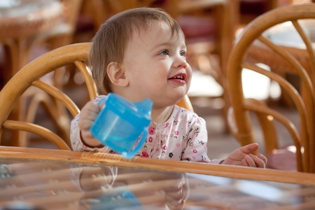 Toddler with baby bottle sitting in resort cafeの写真素材