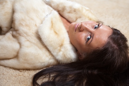 Sexy woman in fur coat laying over  rugの写真素材