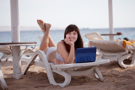 Happy  woman  with laptop at resort beachの写真素材