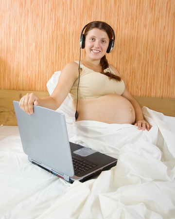 pregnant woman sitting on sofa with laptopの写真素材